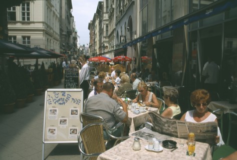 HUNGARY, Budapest, People at outside tables of restaurant with woman reading Hungarian newspaper in