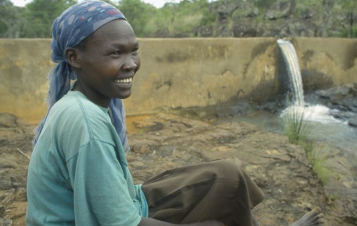 KENYA, Kipsaraman, Pauline Rerimoi beside dam she built.  Previously she had had to carry a twenty
