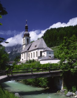 GERMANY, Bavaria, Ramsau, View over river and wooden bridge towards Ramsau Church and wooded