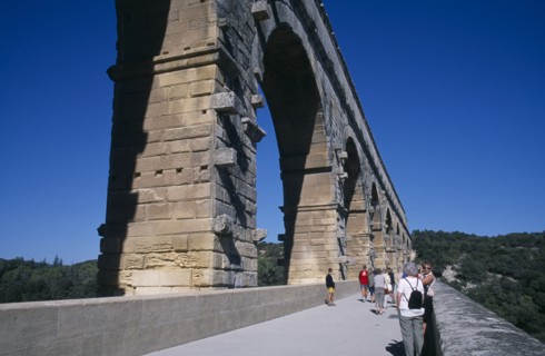 FRANCE, Languedoc Roussillon , Gard, Pont du Gard Roman aqueduct.  Tourists on bridge beside arches