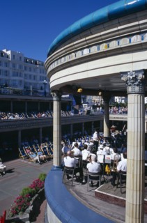 20059184 ENGLAND East Sussex Eastbourne View over the Promenade Band Stand with a brass band performing on a sunny day with spectators watching from deckchairs