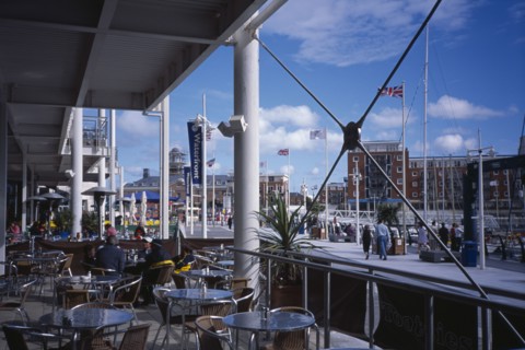 20059200 ENGLAND Hampshire Portsmouth Gunwharf Quay Shopping Centre. Outside Cafe with view across table and chairs and exterior structures.