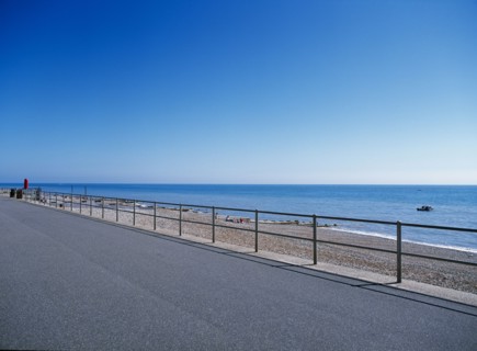 20059214 ENGLAND East Sussex Bexhill on Sea View from path across railings towards shingle beach and calm blue sea.