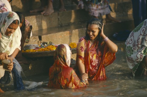 INDIA, Uttar Pradesh, Varanasi, Women wearing saris bathing in the sacred ghats on the River ganges