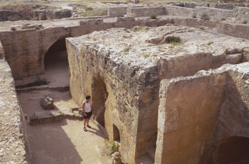 CYPRUS, Paphos, Tomb of the Kings with tourist looking through entrance.