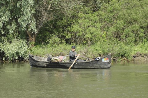 ROMANIA, Tulcea, Danube Delta, Fisherman transporting cycle and goods in a country boat in Danube
