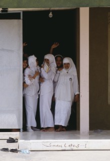 INDONESIA, Java, Muslim college girls dressed in white standing at a door entrance.
