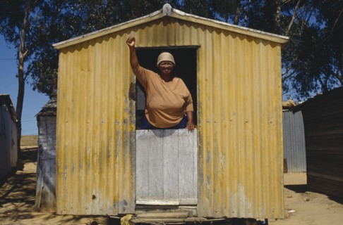 SOUTH AFRICA, Western Cape, Malmsbury, Woman standing with her fist in air looking out of a yellow
