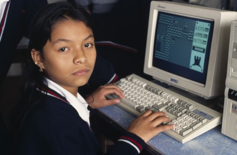 PERU, Lima, School girl learning computer sitting in class looking towards camera.