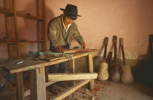 BOLIVIA, Chuquisaca, Tarabuco, Charango musical instrument maker at workbench.