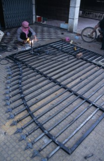 CAMBODIA, Siem Reap, Man welding a metal gate which is lying on the ground