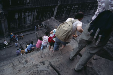 CAMBODIA, Siem Reap Province, Angkor Wat, Line of tourists climbing down steep and narrow steps of
