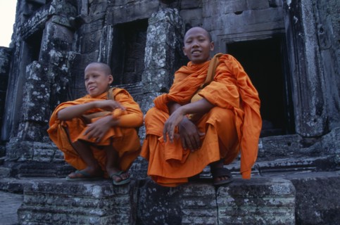 CAMBODIA, Siem Reap, Angkor Thom, Bayon Temple with two monks sitting on the upper level