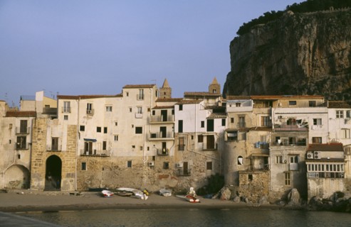 ITALY, Sicily, Cefalu, Town houses on edge of water with huge rock behind once the site of a Temple