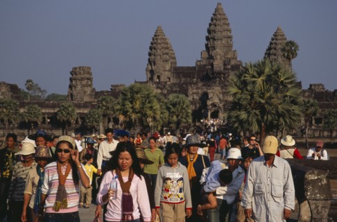 CAMBODIA, Siem Reap Province, Angkor Wat, Tourists on stone causeway leading to temple complex.