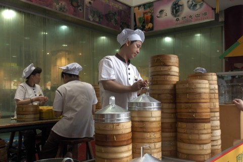 CHINA, Shanghai, Restaurant with stacked bamboo steamers and workers dressed in white