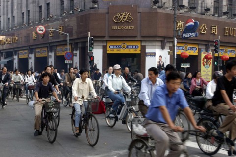 CHINA, Shanghai, Mass of cyclists passing a crossroads at the traffic lights outside the Hui Luo Co