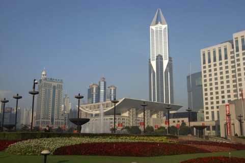 CHINA, Shanghai, Modern city skyline seen over formal garden in the foreground