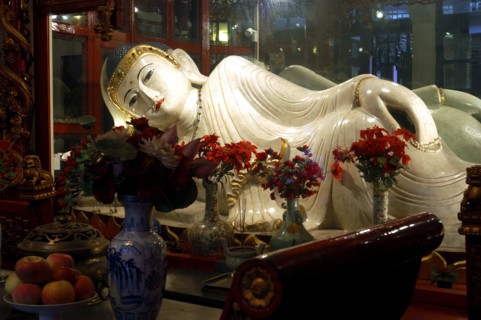 CHINA, Shanghai, Jade Buddha Temple. Reclining Buddha statue with flower vases in front