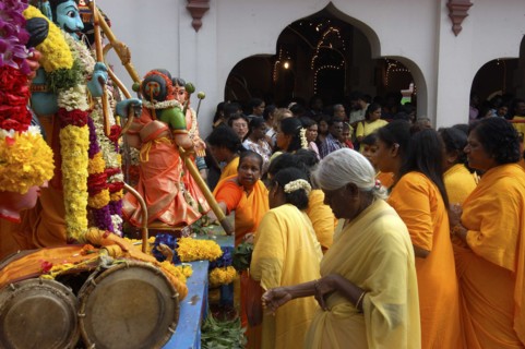 SINGAPORE, , Women standing beside a colourful shrine decorated with flower garlands at an Indian