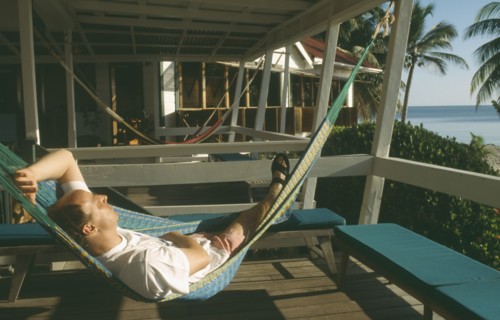 BELIZE, Placencia, Man relaxing in hammock at the Rum Point Inn