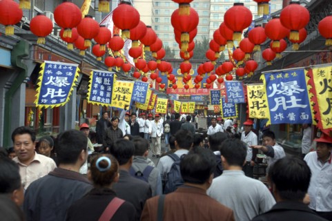 CHINA, Beijing, Busy street scene with red lanterns hanging in rows overhead