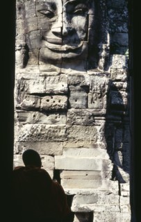 CAMBODIA, Siem Reap, Angkor Thom, Bayon Temple with a monk sitting in a doorway in front of one of