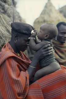 UGANDA, Karamoja, Portrait of Karamojong warrior holding his baby.