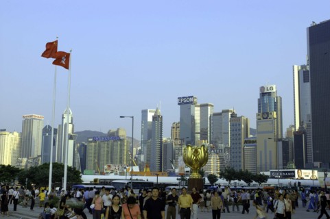 HONG KONG, General, Busy street scene with city skyline and crowds of people in the foreground