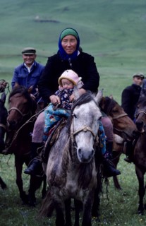 CHINA, Xinjiang Province, Kazakh mother and young child travelling on horseback