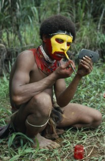 PAPUA NEW GUINEA, Southern Highlands, Tari Valley, Huli tribesman painting his face using old car