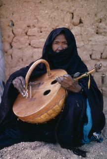 NIGER, Tribal Music, Tuareg woman playing an Imzad.  Traditional instrument consisting of a