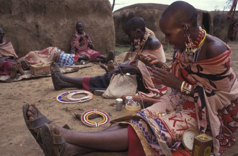 KENYA, , Maasai women making traditional crafts in a cultural  manyatta set up for tourists on the