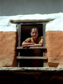 NEPAL, Tatopani Village, Girl framed by her wooden window
