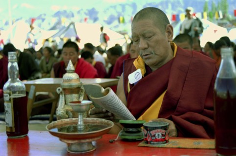 INDIA, Ladakh, Monk sitting at a table reading at the 14th Dalai Lamas birthday celebrations