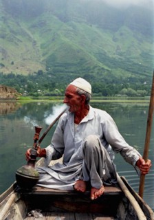 INDIA, Kashmir, Srinagar, Nagin Lake. Man sitting in boat smoking a Hookah pipe