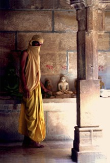 INDIA, Rajasthan, Mt Abu, Fly monk standing near Buddha statues with a scarf covering his head and
