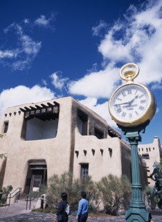 USA, New Mexico, Santa Fe, Museum with typical Adobe architecture and large clock in the foreground