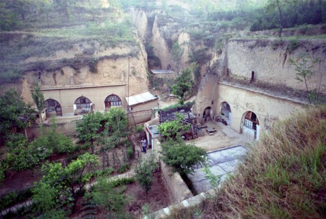 CHINA, Shaanxi, Yulin, View over cave dwellings built into the cliffside with man tending to