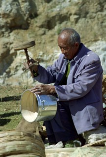 CHINA, Yunnan, Shapin, Man using old style drilling tool on metal and wooden pot