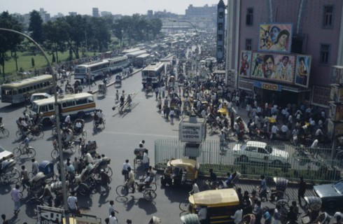 BANGLADESH, Dhaka, Busy street scene with crowds of pedestrians trishaws and buses.  Cinema with