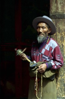 CHINA, Tibet, Lhasa, Portrait of a man spinning a mini Prayer Wheel at the Jokhang Temple
