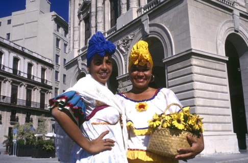 CUBA, Havana, Two smiling women wearing brightly coloured head scarfs standing in the square