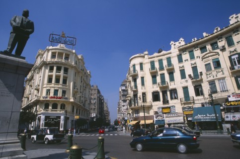 EGYPT, Cairo , Midan Talaat Harb.  Traffic on city road lined by cream coloured buildings with