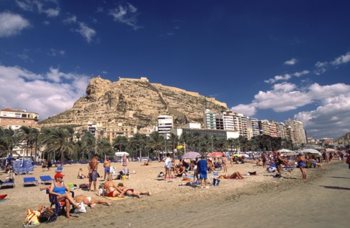SPAIN, Alicante, Busy beach scene with clifftop castle beyond