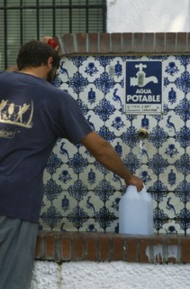 SPAIN, Andalucia, Granada, Lanjaron. Man collecting water from a drinking fountain in this Sierra