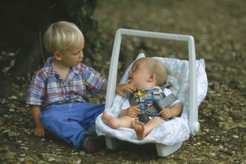 FRANCE, Dordogne, Young boy sitting with his baby brother in a baby carrier