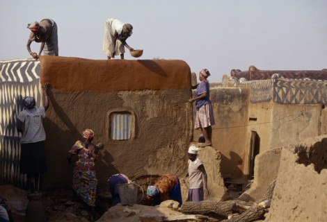 BURKINA FASO, Tiebele, Group of women preparing house front for decorative painting in traditional