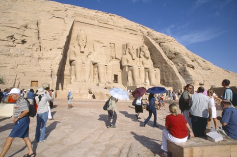 EGYPT, Nile Valley, Abu Simbel, Sun Temple of Ramses II.  Tourists outside entrance flanked by four