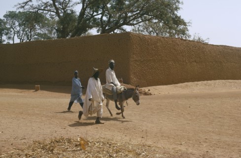 NIGERIA, Kano, Street scene with two men walking beside a man on a donkey